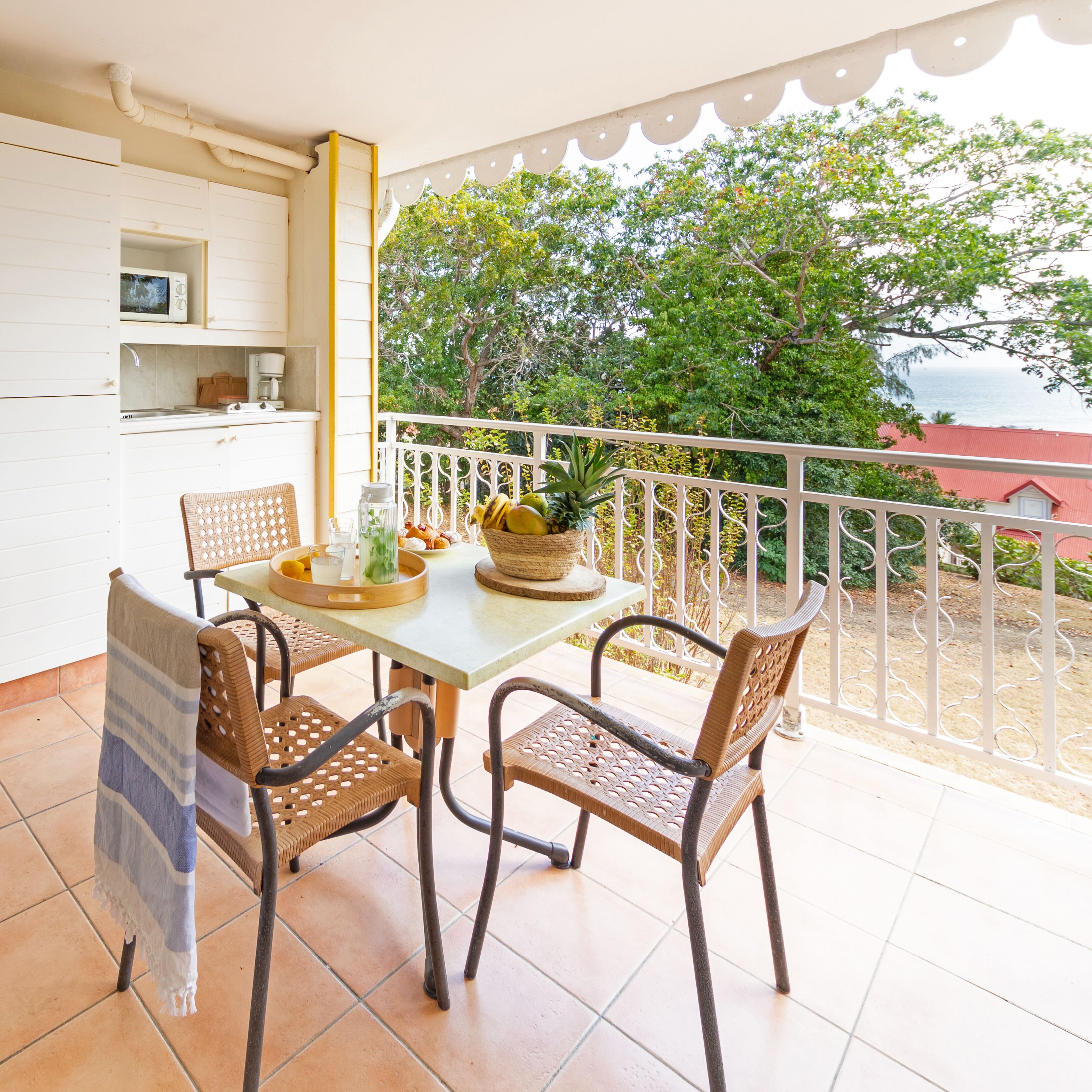 Un balcon avec une table, des chaises et un pot de fleurs.