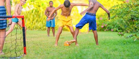 A group of people playing soccer on a grassy field with a goalpost.