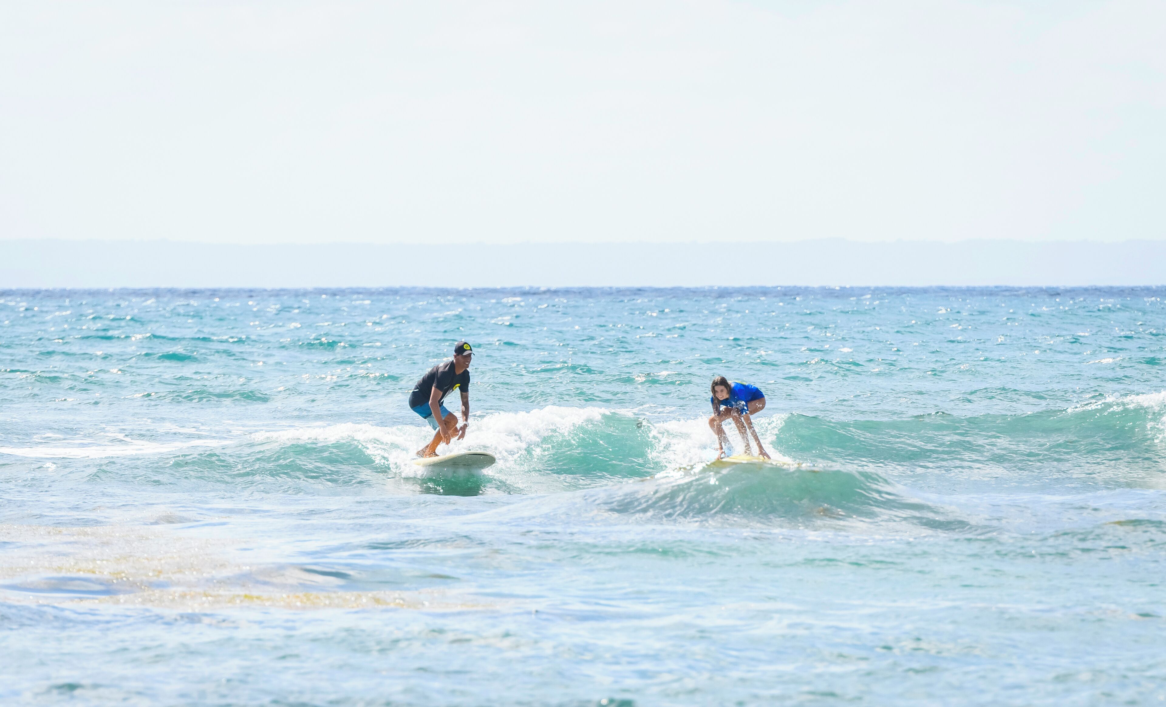 Dos personas surfeando en un mar tranquilo.