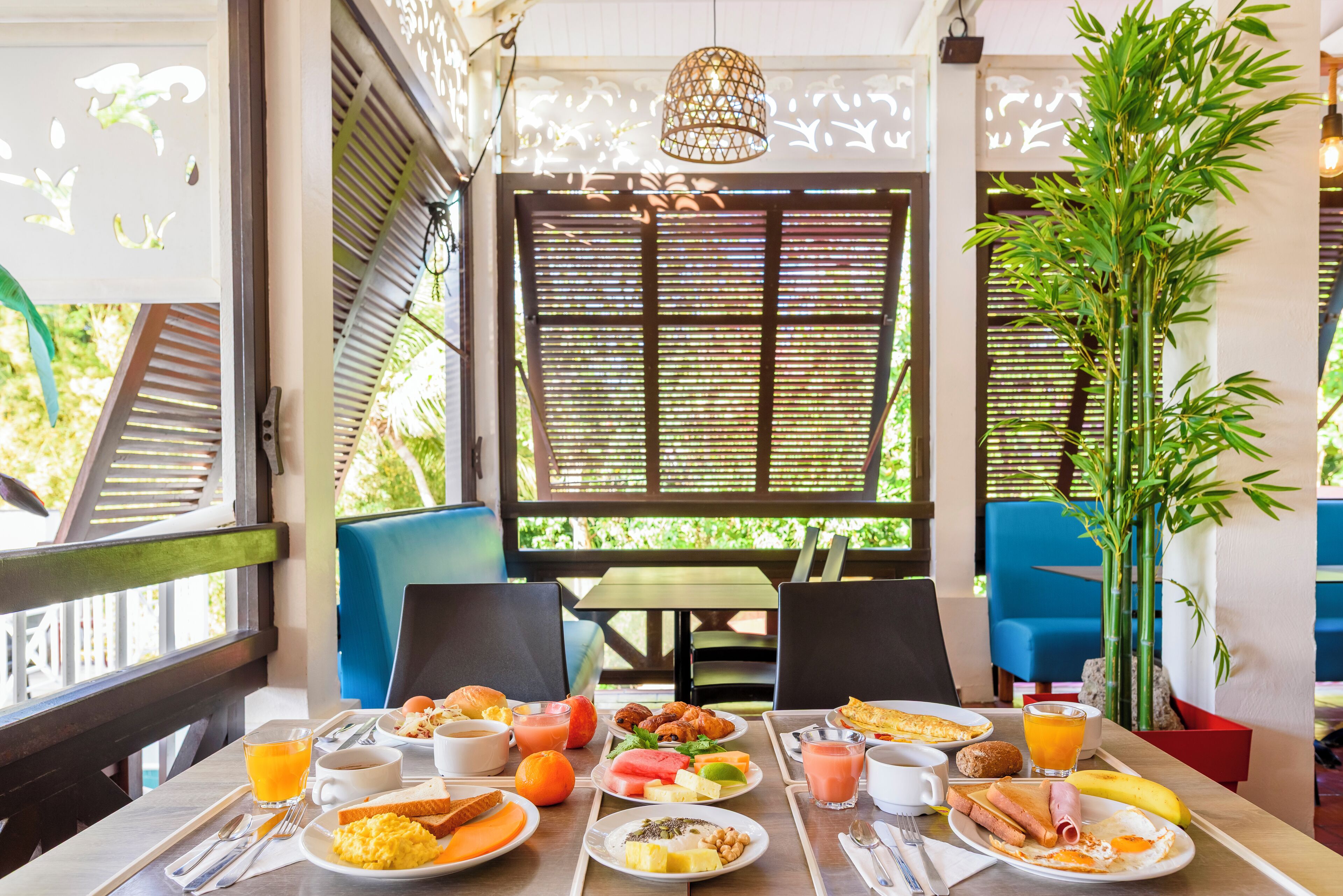 Une table de petit-déjeuner dressée avec des assiettes remplies de nourriture, des boissons et des couverts.