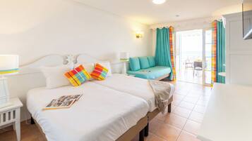 Habitación de hotel con una cama grande, un pequeño sofá, un rincón de comedor y vistas al exterior.