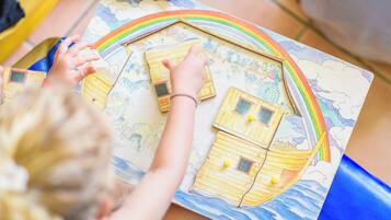 A child playing with a colorful board game featuring a rainbow and houses.