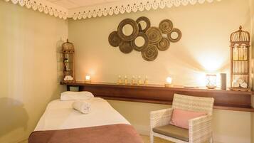 Una habitación con una cama, una silla, una pared con espejos circulares y una estantería con botellas y una lámpara.