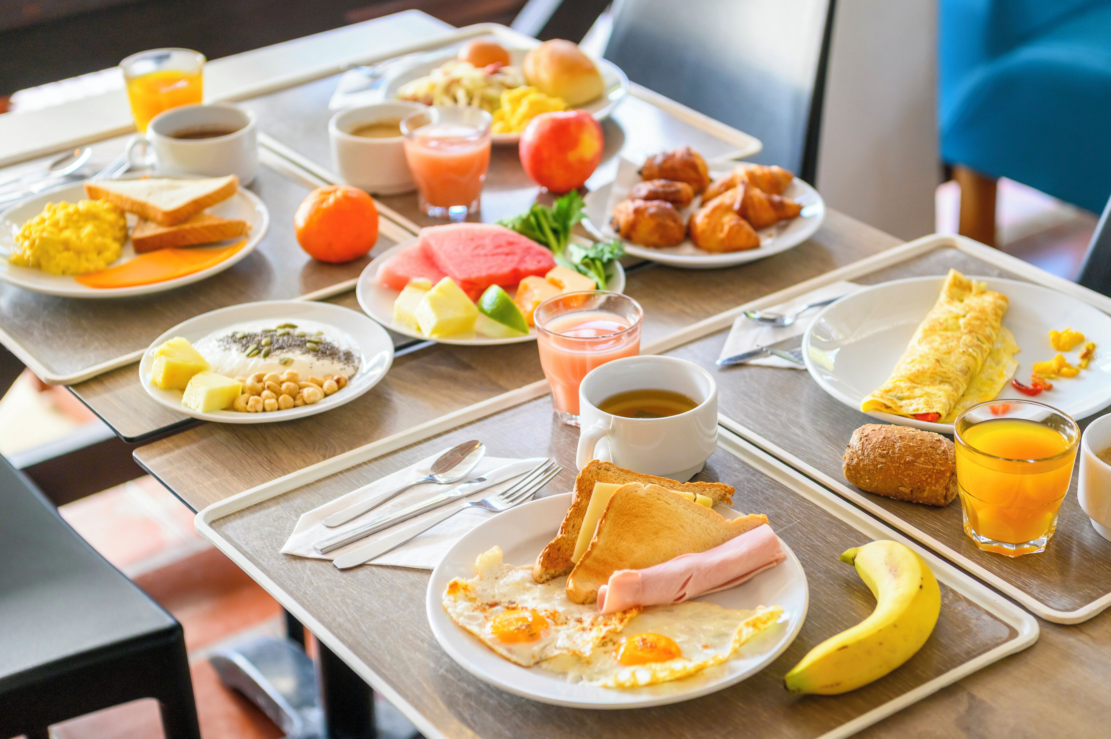 Un buffet de petit-déjeuner proposant divers plats, notamment des œufs, des toasts, des fruits et des boissons.