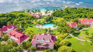An aerial view of a resort with a central pool, surrounded by lush greenery and beachfront properties. - Village St Anne Pierre & Vacances (Sainte-Anne)