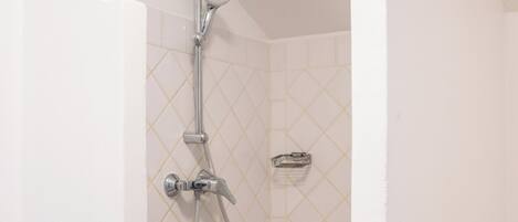 Une douche équipée d’un pommeau de douche à main et d’un robinet fixé au mur.