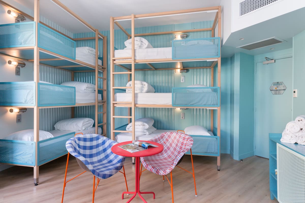 Une chambre avec des lits superposés, une petite table et deux chaises.