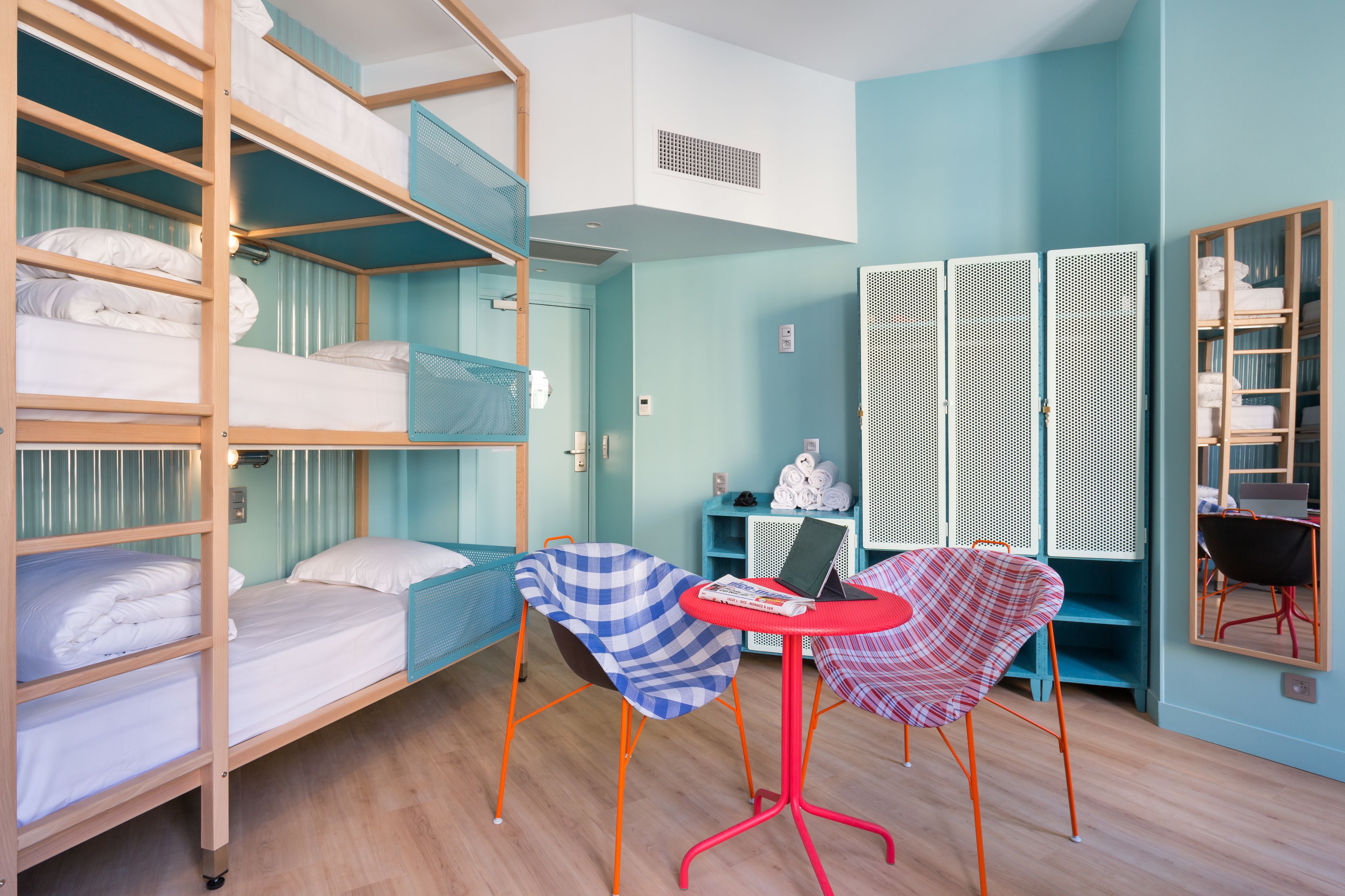 Une chambre de type dortoir avec des lits superposés, une petite table avec un ordinateur portable et une chaise.