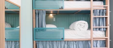 Une chambre avec un lit superposé, une échelle, des rideaux et une petite étagère.