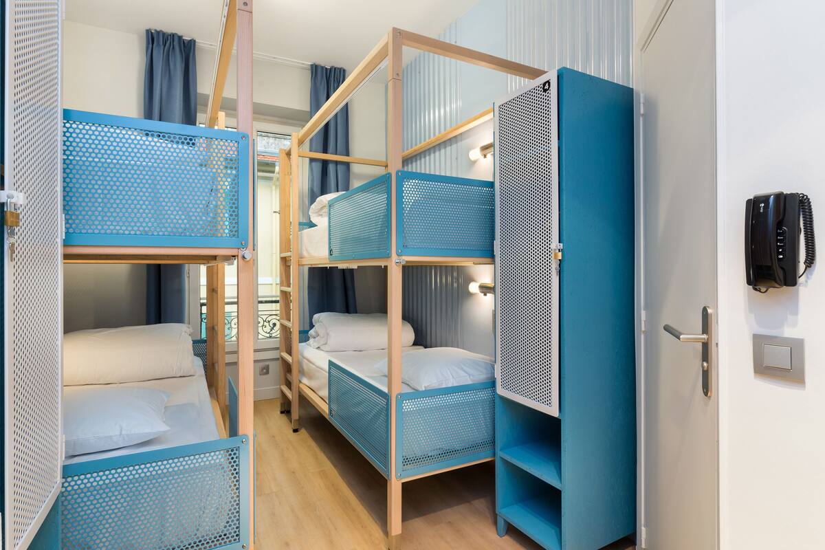 Une chambre de dortoir équipée de lits superposés, d’une armoire et d’un téléphone.