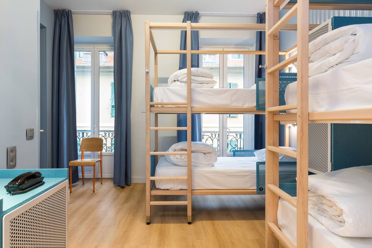 Une chambre d’hôtel avec des lits superposés, un bureau avec un téléphone et une chaise.