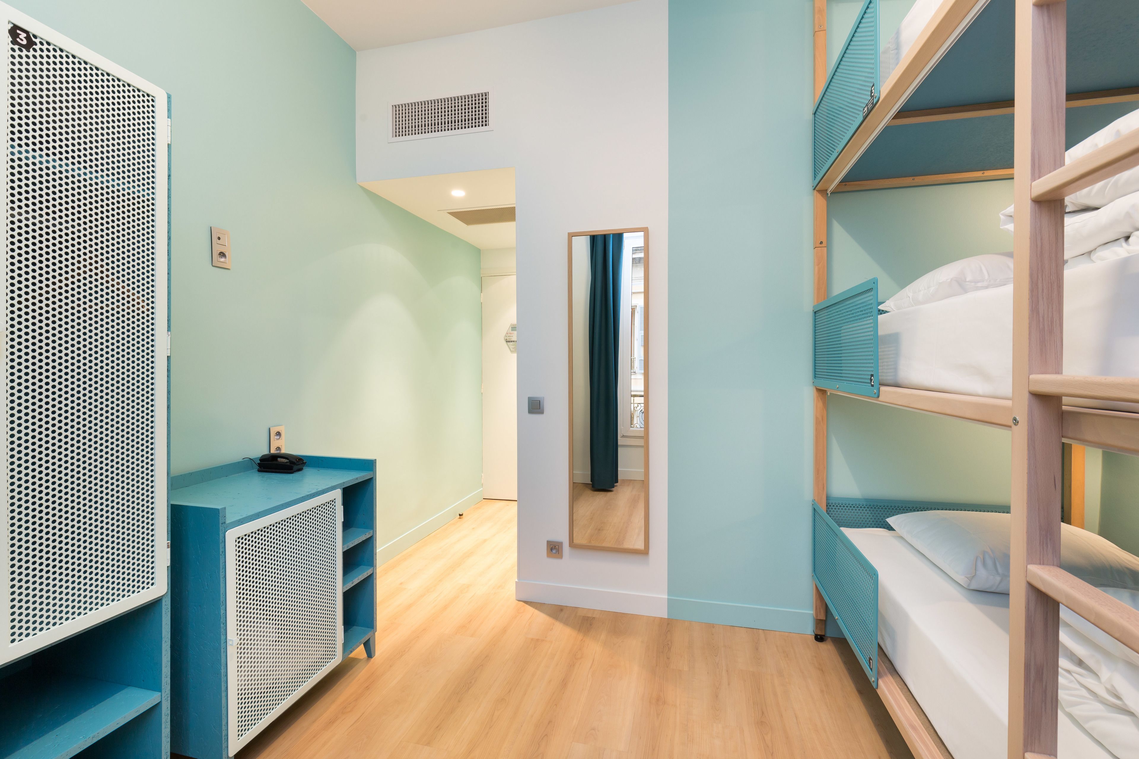 A room with bunk beds, a blue console table, and a mirror.
