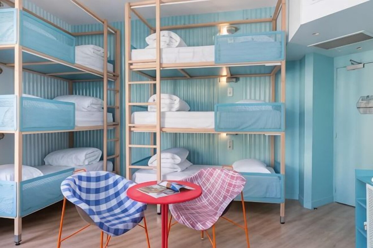 Une chambre de dortoir avec des lits superposés, une petite table et une chaise.