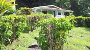 A house surrounded by lush greenery and a stone pathway. - Chez Ophelia Cottage Apartments (Roseau)