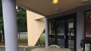 Een buitenruimte met zitplaatsen, een tafel, stoelen, een afvalbak en een beveiligingscamera.