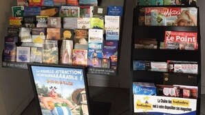Een presentatie van tijdschriften en boeken met een bord waarop een nieuwe attractie wordt aangekondigd.