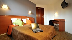 Een hotelkamer met een bed, een bureau en een laptop.