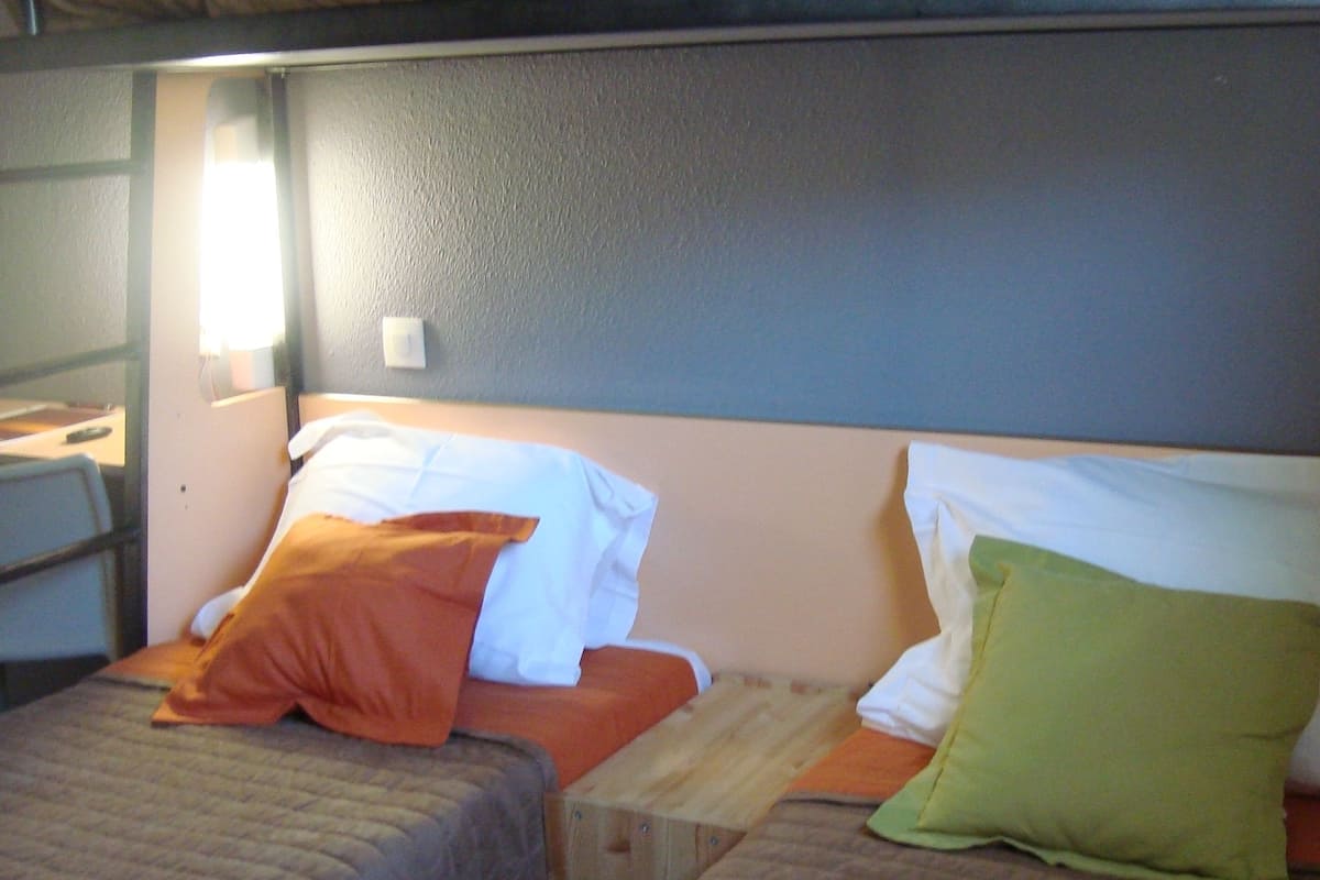 Een slaapkamer met een stapelbed, met twee bedden, elk voorzien van kussens en een gewatteerde deken.