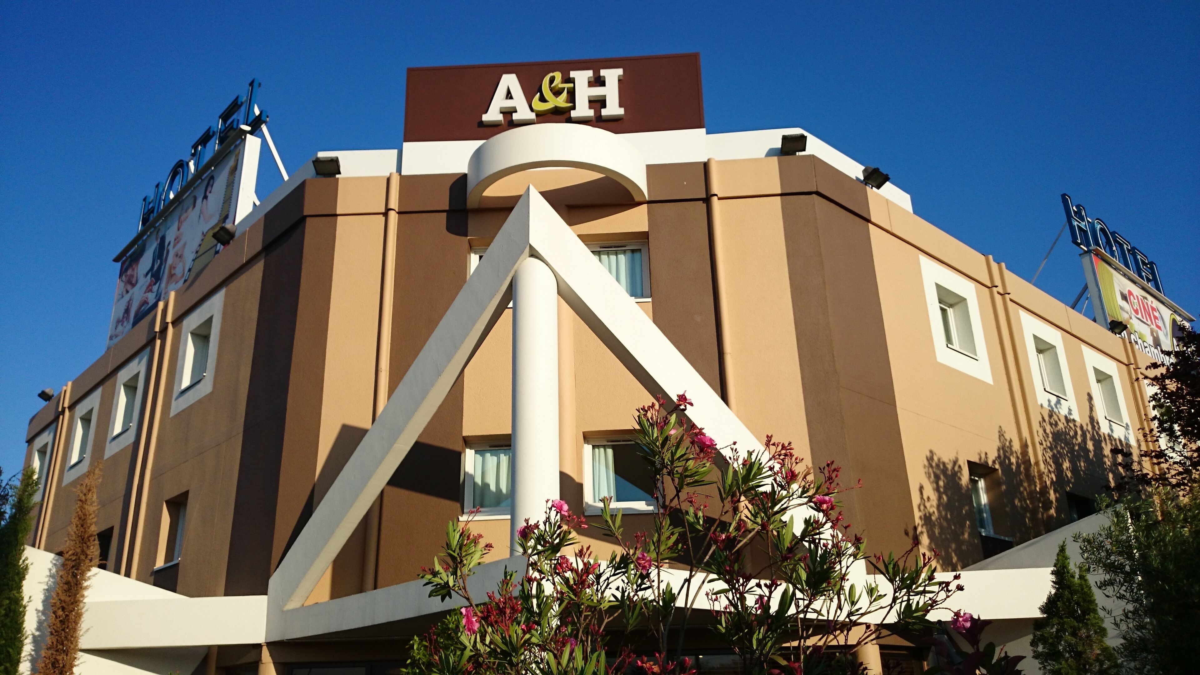 Un edificio con un llamativo letrero de A&H, diseño arquitectónico moderno y un letrero de Cineplex.