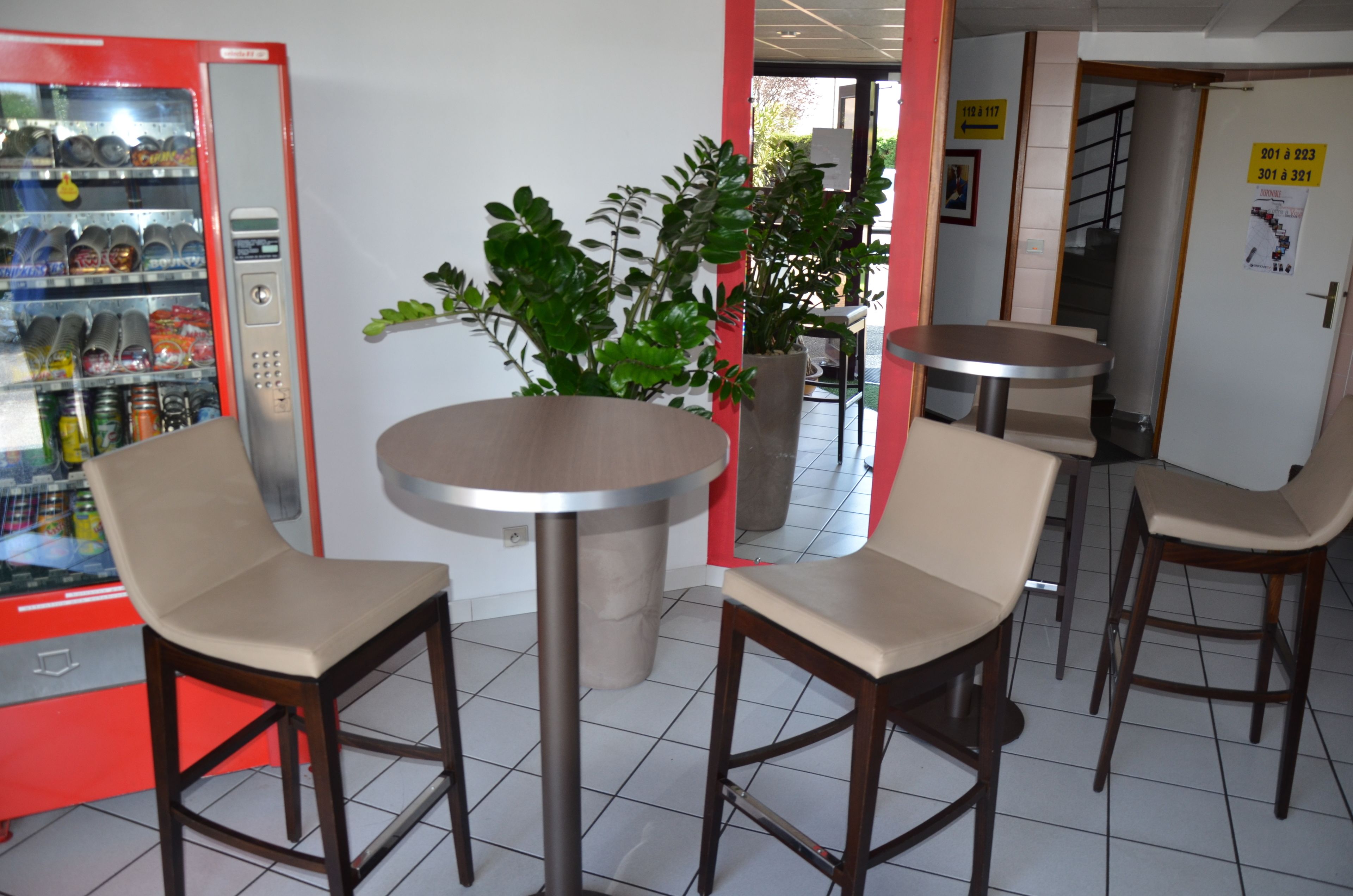 L’intérieur d’un restaurant avec un distributeur automatique, des tables rondes et des tabourets de bar.