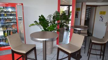 L’intérieur d’un restaurant avec un distributeur automatique, des tables rondes et des tabourets de bar.