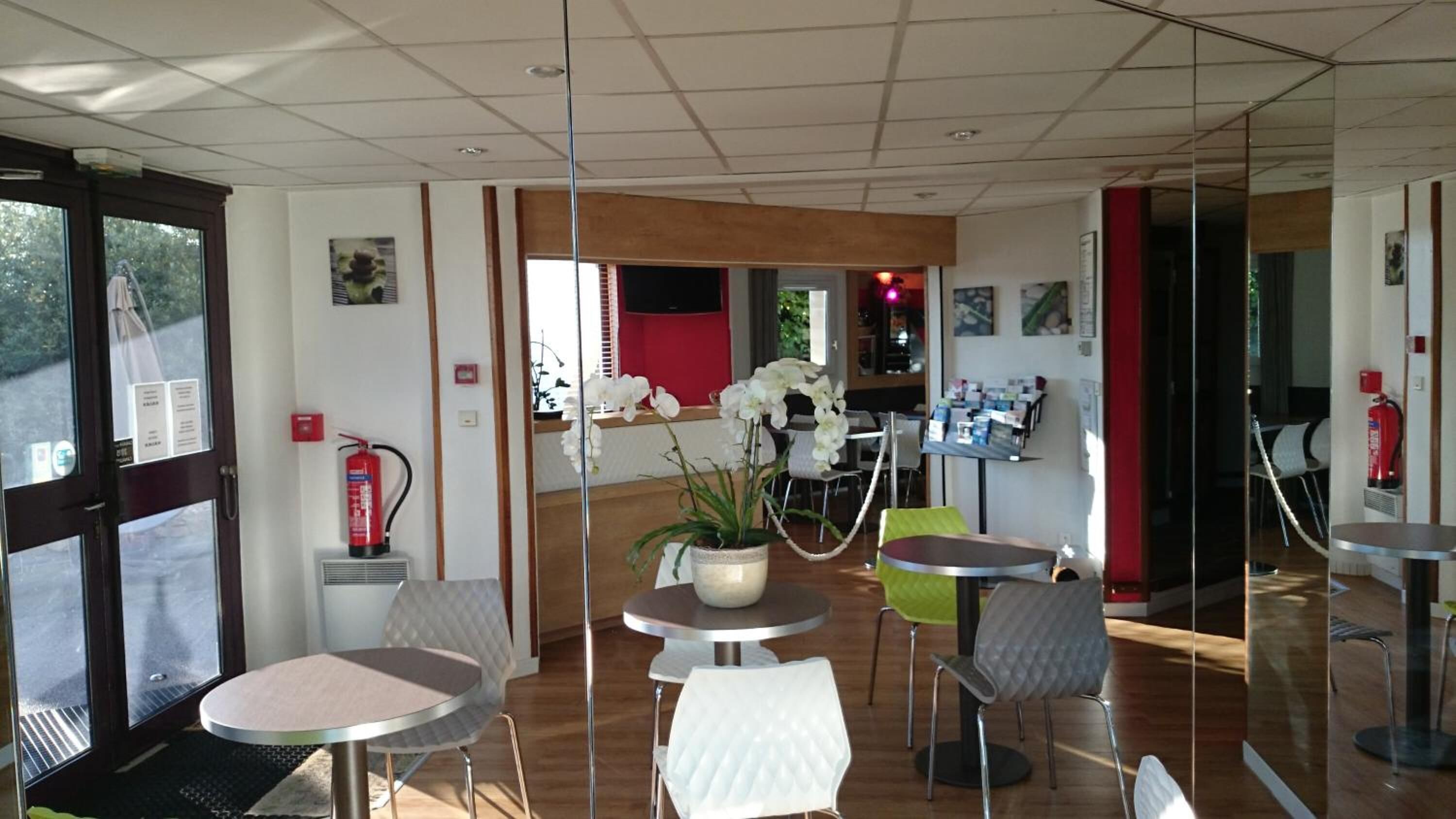 A modern interior with round tables and chairs, a fire extinguisher, and a potted plant.