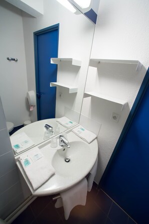 Une salle de bain avec un lavabo blanc, un miroir, une porte bleue et un porte-serviettes blanc.