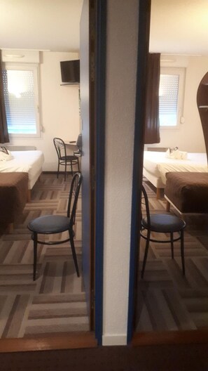 Une chambre avec deux lits, un bureau et deux chaises.