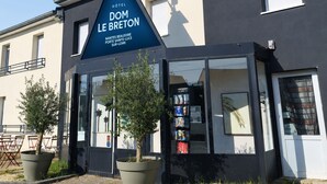 A hotel sign for 'DOM LE BRETON' with a modern facade, large windows, and a solar panel. - Hotel Dom le Breton Nantes Beaujoire - Porte de Sainte Luce (Sainte-Luce-sur-Loire)