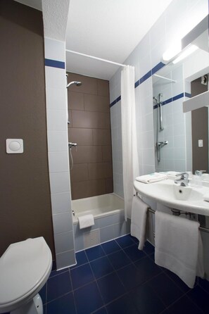 Une salle de bain comprenant des toilettes, une baignoire et un lavabo avec un miroir.