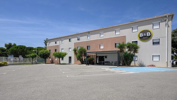 Un hotel B&B con estacionamiento, mesas al aire libre y un letrero que indica accesibilidad.