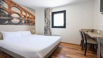 Une chambre d’hôtel avec un lit, un bureau avec des chaises, une fenêtre et une fresque représentant un pont.