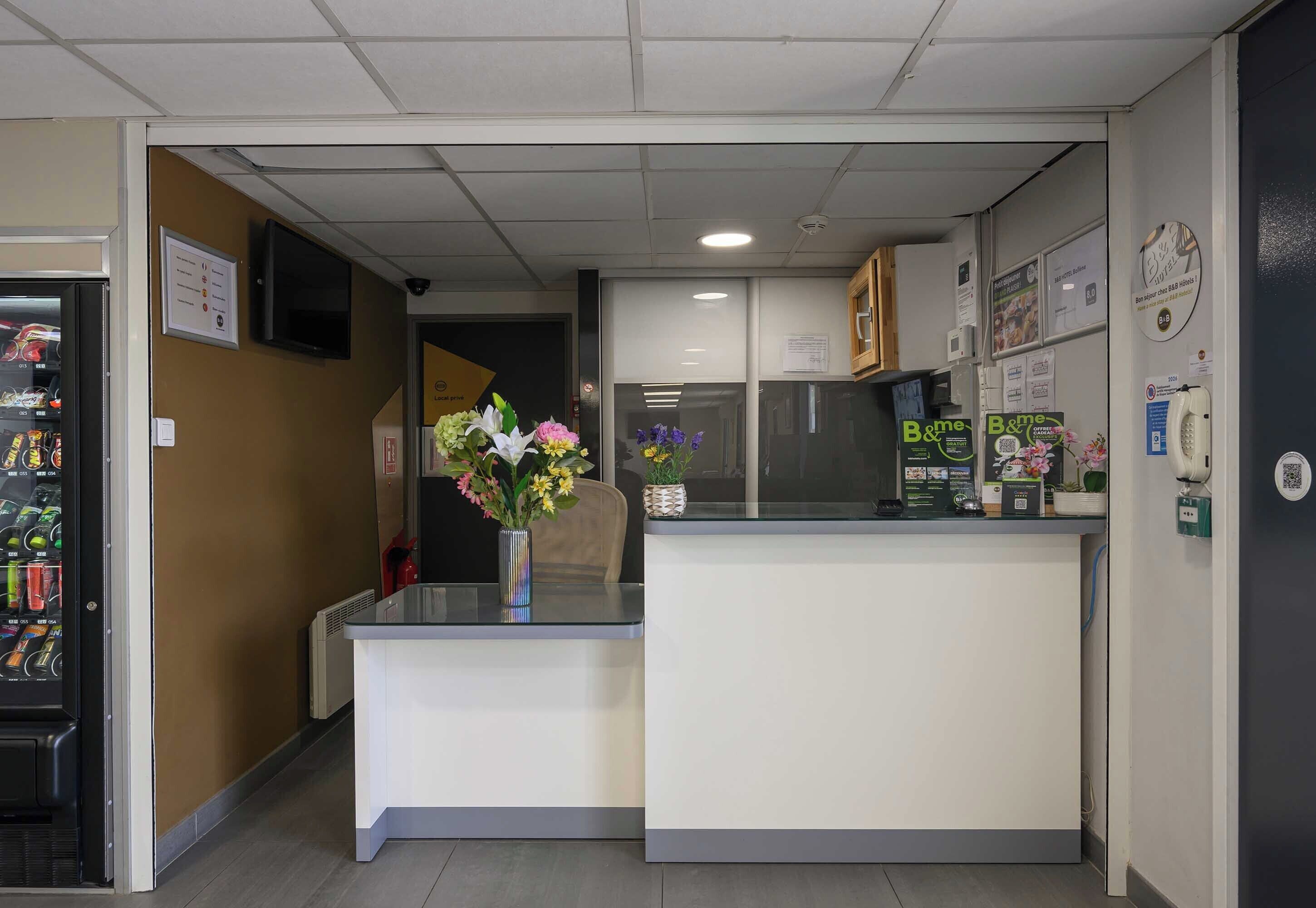Un espace d’accueil comprenant un comptoir, un distributeur automatique et un téléphone fixé au mur.