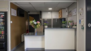 Zona de recepción con mostrador, máquina expendedora y teléfono en la pared.