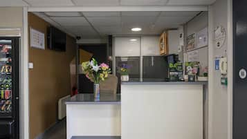 Un espace d’accueil comprenant un comptoir, un distributeur automatique et un téléphone fixé au mur.