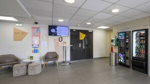 A reception area with a digital clock, a vending machine, and seating. - B&B HOTEL BOLLENE (Bollene)