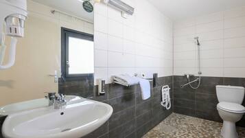 A bathroom with a sink, mirror, towel rack, shower, and toilet.