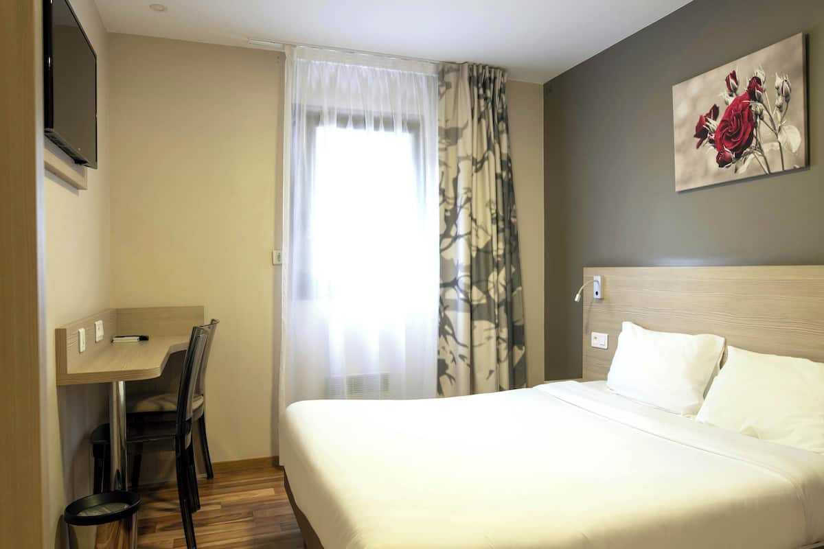 Hotellihuone, jossa on sänky, työpöytä ja tuoli.