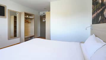 A hotel room with a bed, a wardrobe, and a bathroom door.