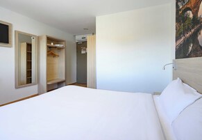 Habitación de hotel con cama, armario y puerta al baño.