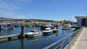 A marina with boats docked, a pier, and buildings in the background.