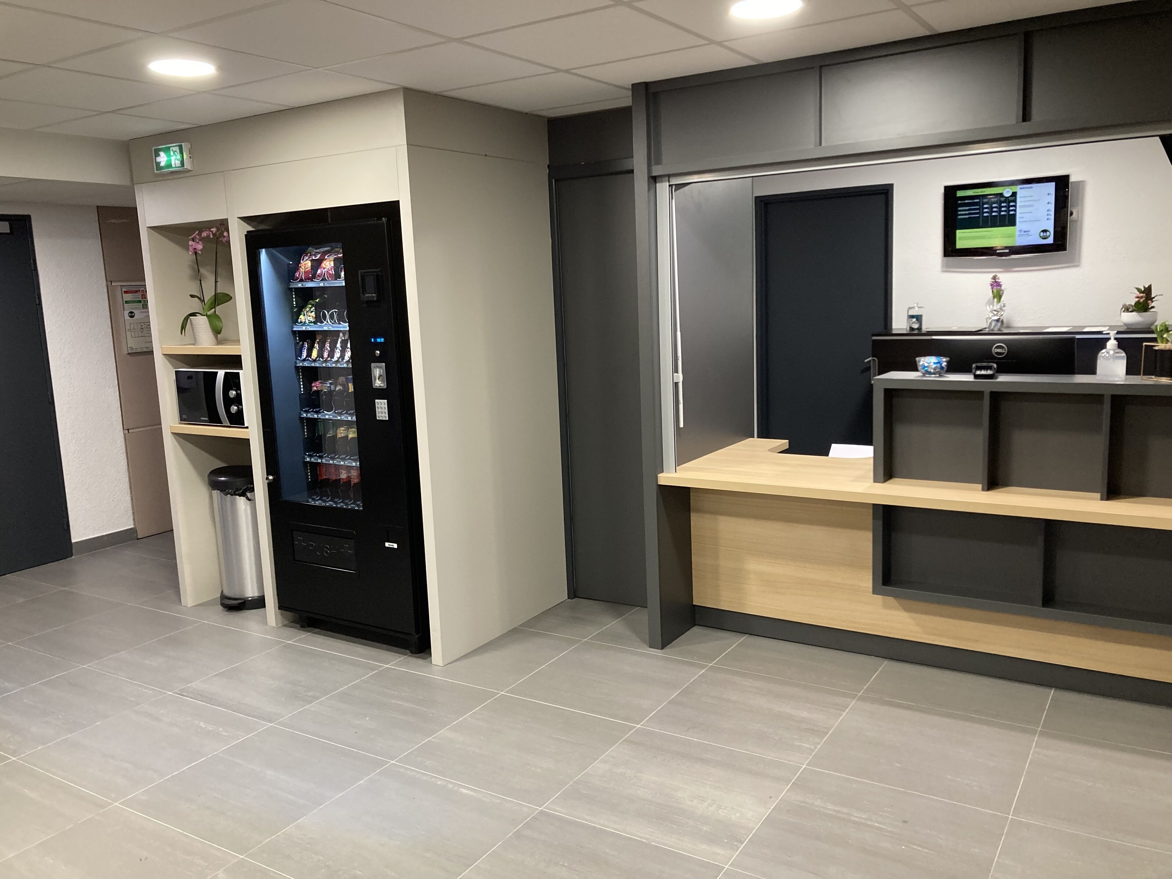 Un'area reception con distributore automatico, scrivania della reception e display digitale.