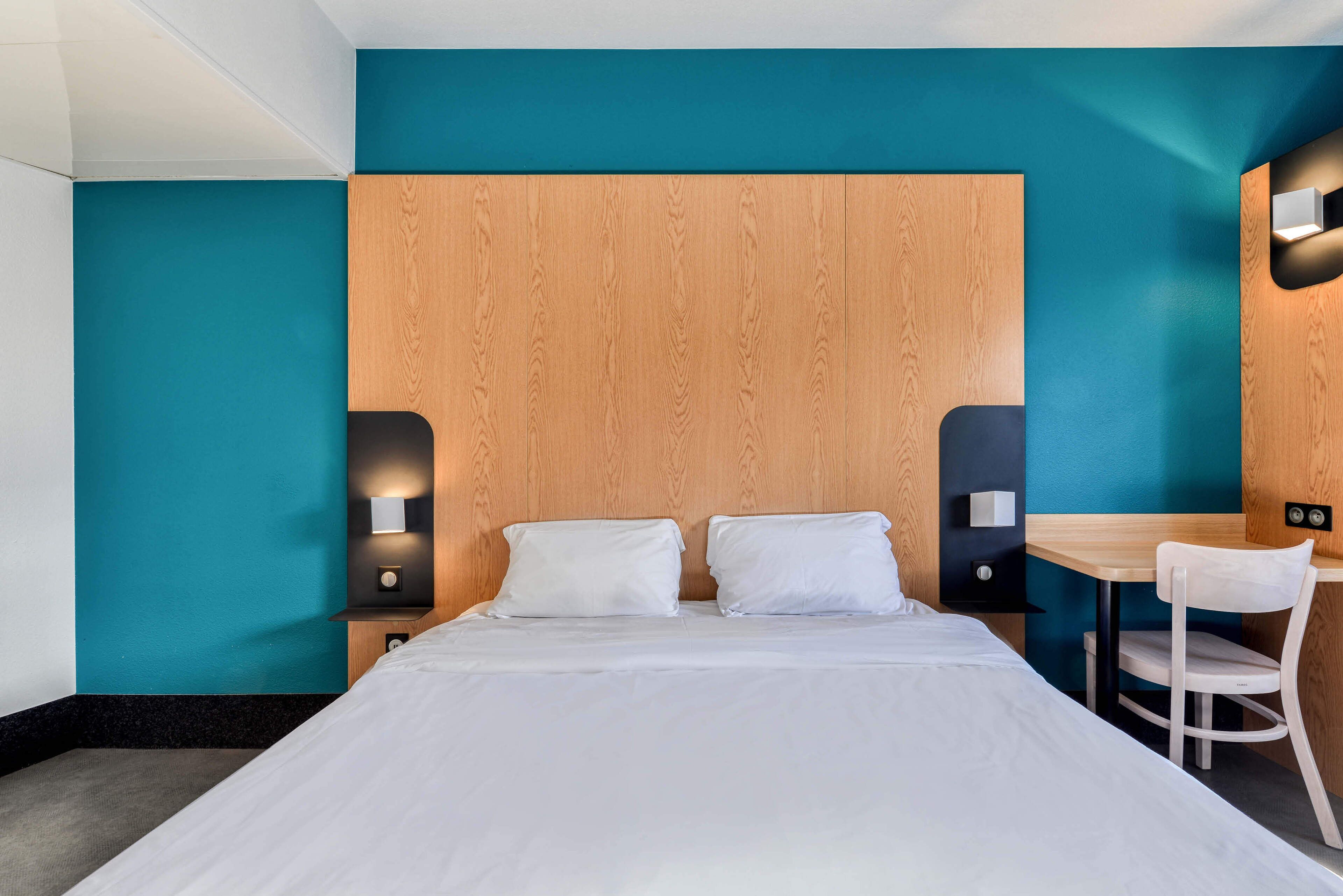 Een moderne hotelkamer met een groot bed, een bureau en een stoel.