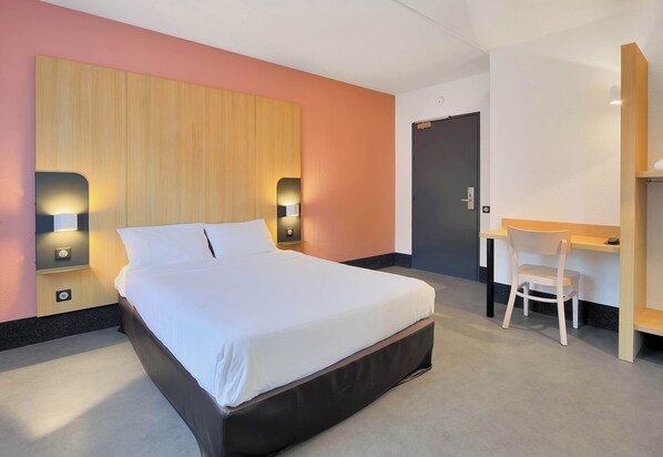Une chambre d’hôtel moderne avec un grand lit, des lampes de chevet, un bureau et une chaise.