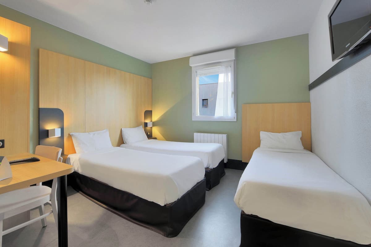 A hotel room with two single beds, a desk, and a chair.