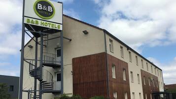 A B&B hotel with a sign, a staircase, and a wooden facade.
