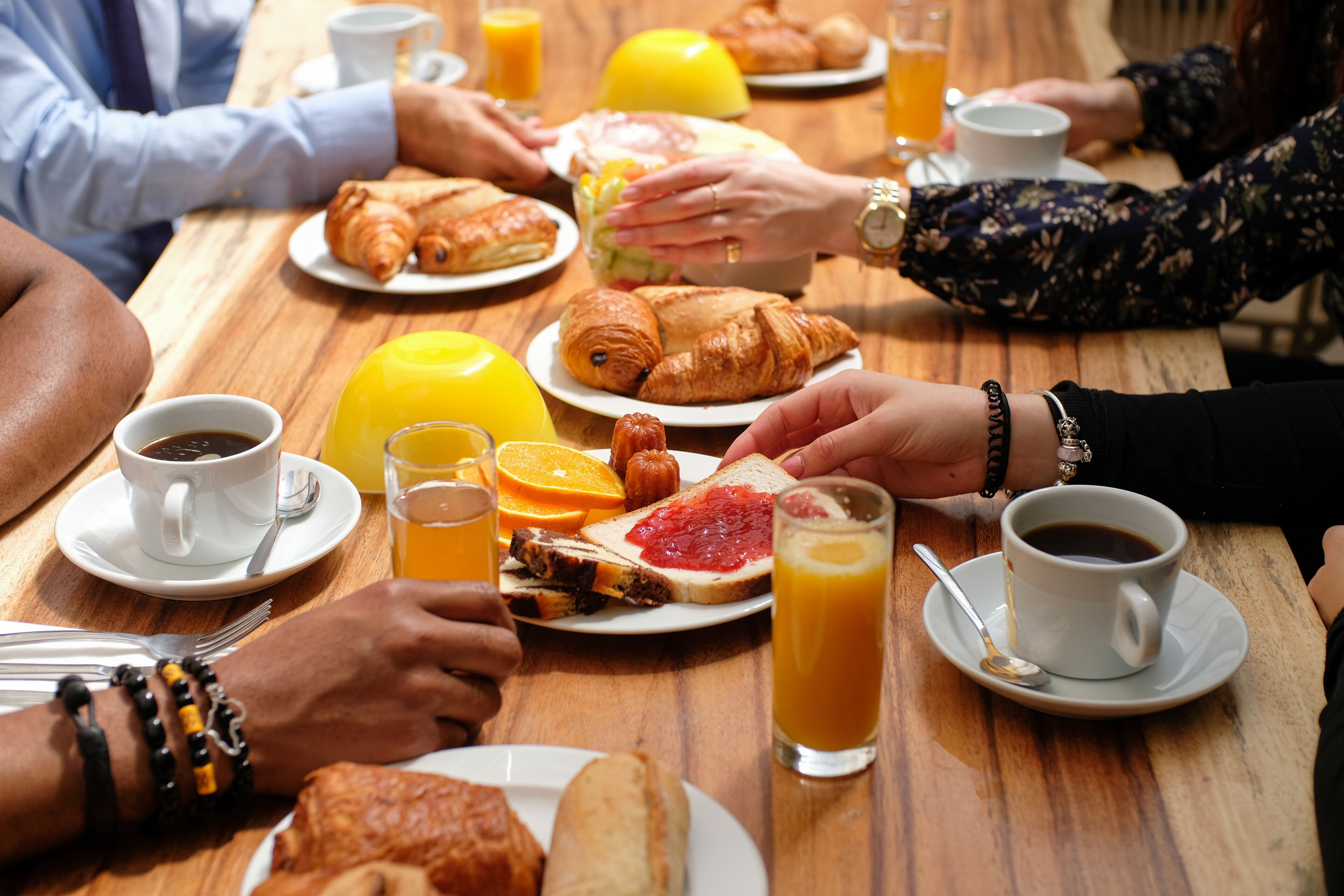 A wooden table with breakfast items including croissants, orange slices, and juice.
