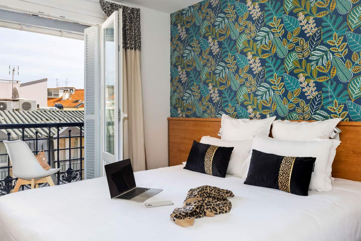 Quarto de hotel com cama, um laptop e vista para o exterior.