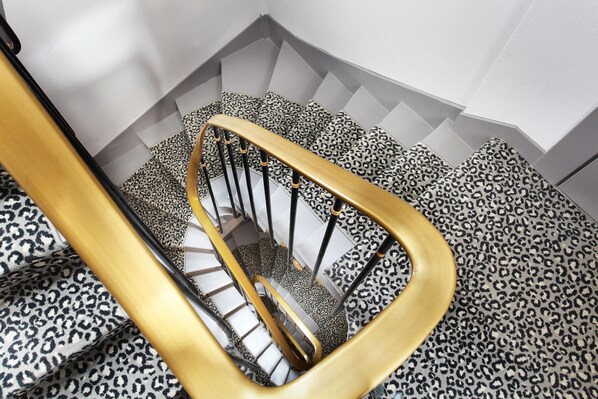 A staircase with a leopard print carpet and a golden handrail. - Garden Saint Martin (Paris)