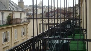 Een balkon met een metalen hekwerk, een trap en een uitzicht op een stadsbeeld, inclusief een gebouw met een koepel.